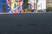 the street is deserted in this city with colorful graffiti walls on the building side and street art