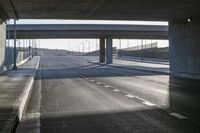 a man on a motorcycle passes under a bridge on a highway with empty lanes in a deserted city