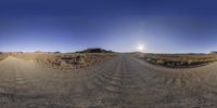 a 360 - ray view of a deserted dirt road at the base of a hill