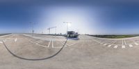 a wide angle fish eye image shows a deserted highway with white markings and buildings on either side