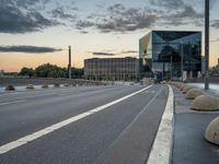 a deserted highway is shown in a city at sunset with a glass building near by