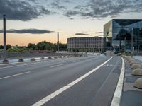 a deserted highway is shown in a city at sunset with a glass building near by