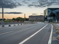 a deserted highway is shown in a city at sunset with a glass building near by