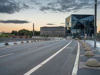 a deserted highway is shown in a city at sunset with a glass building near by