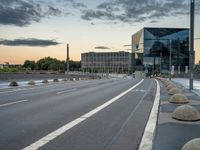 a deserted highway is shown in a city at sunset with a glass building near by