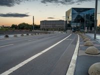 a deserted highway is shown in a city at sunset with a glass building near by