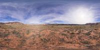 the road is deserted on the desert floor, there are clouds and a mountain range