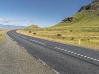 a deserted empty highway winding past some mountains with a sky background in iceland, scandinavia