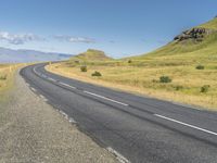 a deserted empty highway winding past some mountains with a sky background in iceland, scandinavia