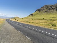 a deserted empty highway winding past some mountains with a sky background in iceland, scandinavia