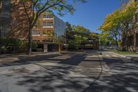 a deserted intersection near the buildings of a large city park in autumn, with a blue sky overhead