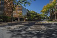 a deserted intersection near the buildings of a large city park in autumn, with a blue sky overhead