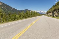 a deserted mountain highway with a few trees in the mountains behind it and a lone mountain range