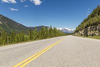 a deserted mountain highway with a few trees in the mountains behind it and a lone mountain range