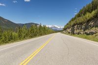 a deserted mountain highway with a few trees in the mountains behind it and a lone mountain range