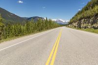 a deserted mountain highway with a few trees in the mountains behind it and a lone mountain range