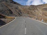 a deserted mountain road that has been paved with rocks and gravels, leading into the distance there are large rocks