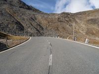 a deserted mountain road that has been paved with rocks and gravels, leading into the distance there are large rocks