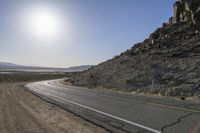 a motorcycle riding down a winding highway between hills and dry grass on a sunny day