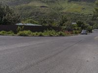 cars are parked in the street at the edge of this deserted neighborhood with a mountain behind them