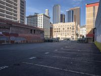 a deserted parking lot is shown with graffiti on the wall and tall buildings in the background