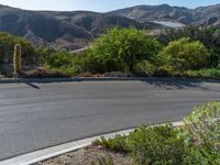 the view across a deserted road at a mountain with cactuss and rocks in it