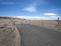 a paved beach with a fence in front of it and the ocean in the distance