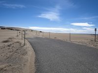 a paved beach with a fence in front of it and the ocean in the distance