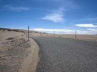 a paved beach with a fence in front of it and the ocean in the distance