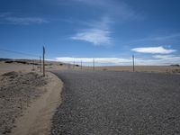 a paved beach with a fence in front of it and the ocean in the distance