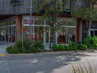 a person is riding a bike past some shops that are closed out and trees have grown in front of the shops