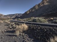 a car driving along a deserted road in the mountainside area of a desert,