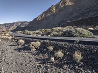 a car driving along a deserted road in the mountainside area of a desert,