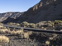 a car driving along a deserted road in the mountainside area of a desert,