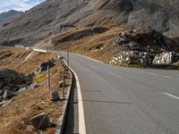 a deserted road with signs on a mountain side near the side of a hill in switzerland