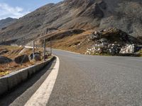 a deserted road with signs on a mountain side near the side of a hill in switzerland