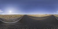 a wide angle view of a deserted road in the desert, showing the lines of road on both sides