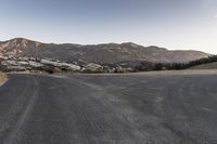 a deserted rural road in the middle of a mountainous area, with mountain peaks in the background