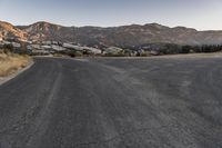 a deserted rural road in the middle of a mountainous area, with mountain peaks in the background