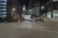 a street is deserted in front of large buildings at night as traffic moves along it