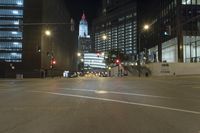 a street is deserted in front of large buildings at night as traffic moves along it