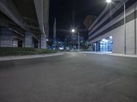 a deserted urban road with the lights on shining in the background and a streetlight overhead