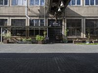 the entrance is next to the street outside of a building with chairs and umbrellas