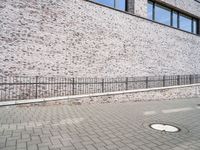 the sidewalk is lined with bricked sidewalk slabs and a metal fence that is next to it