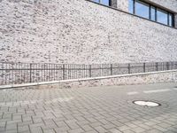 the sidewalk is lined with bricked sidewalk slabs and a metal fence that is next to it