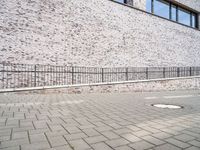 the sidewalk is lined with bricked sidewalk slabs and a metal fence that is next to it