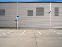 the corner of a parking lot in front of a building with shuttered window openings