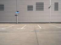 the corner of a parking lot in front of a building with shuttered window openings