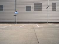 the corner of a parking lot in front of a building with shuttered window openings