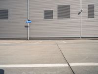 the corner of a parking lot in front of a building with shuttered window openings